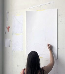 En tjej ritar på ett stort papper på en vägg