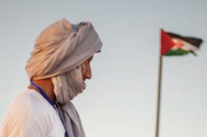 Porträttfoto på Mohamedsalem Werad med en västsaharisk flagga i bakgrunden.