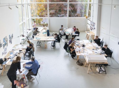 ateljé sedd ovanfrån på designskolan En ljus ateljé på Ölands Folkhögskola sedd uppifrån. Tre bord med grupper som arbetar kreativt på designskolan